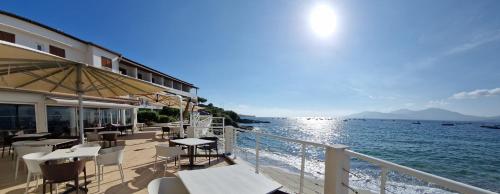 a restaurant with tables and chairs next to the water at Hôtel U Paradisu in Porticcio