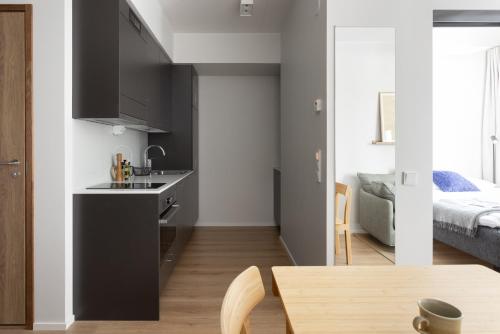 a kitchen with black cabinets and a table and a bed at Noli Otaniemi in Espoo