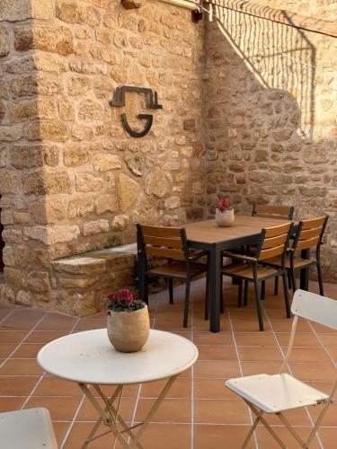 a patio with tables and chairs and a brick wall at APARTAMENTOS VILLA DE GOYA in Fuendetodos