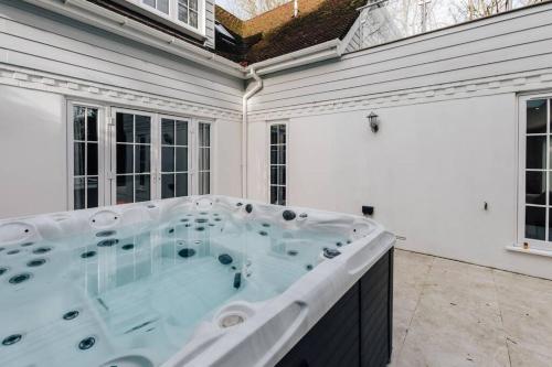 bañera de hidromasaje en una habitación blanca con ventanas en Ferry house, en Marlow
