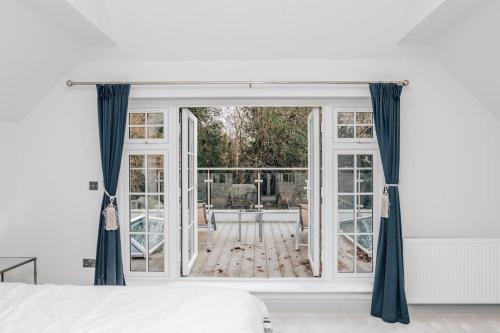 a bedroom with a large window with blue curtains at Ferry house in Marlow