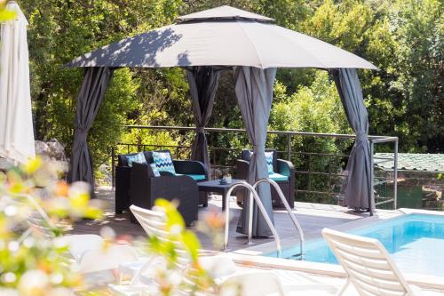 an umbrella and chairs next to a swimming pool at RELAXING HOME LUCE in Čilipi