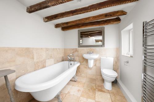 a bathroom with a tub and a toilet and a sink at The Milkhouse Cottage by Huluki Sussex Stays in Ashurst