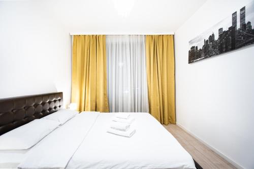 - une chambre avec un lit et une fenêtre avec des rideaux jaunes dans l'établissement Opal Luxury Aviatiei, à Bucarest