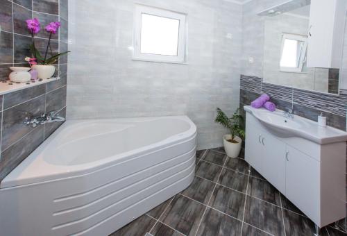 a white bathroom with a tub and a sink at RELAXING HOME LUCE in Čilipi