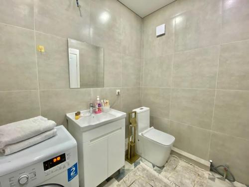 een badkamer met een toilet, een wastafel en een spiegel bij Просторная двухкомнатная квартира в ЖК Ala-Park Егизбаева 3 in Alma-Ata
