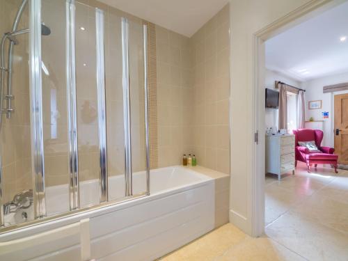 a large bathroom with a tub and a red chair at The Cart Lodge 6 in Great Massingham