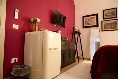 una nevera en una habitación con una pared roja en YOLE Affittacamere en Empoli