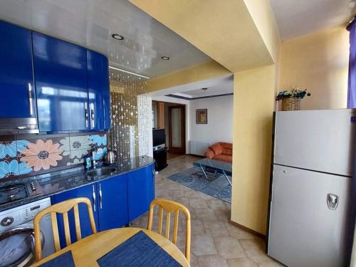 バトゥミにある2 room apartment in Batumiのキッチン(青いキャビネット、テーブル、冷蔵庫付)