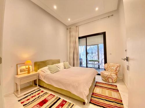 a bedroom with a bed and a chair and a window at Chez Dadou - joli Apt Marsa Safsaf in La Marsa