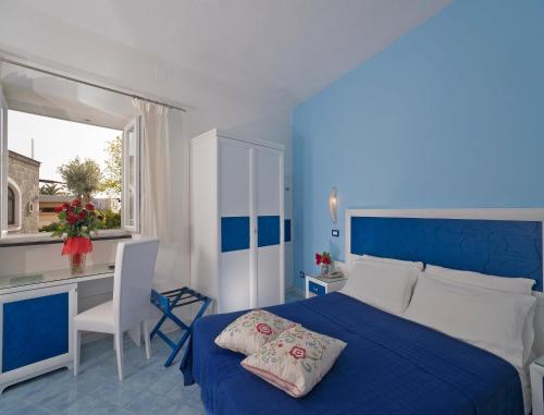 niebiesko-biała sypialnia z łóżkiem i biurkiem w obiekcie Hotel Imperamare w mieście Ischia