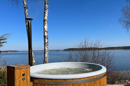 a wooden bath tub sitting next to a body of water at Lustro Wody in Osiek
