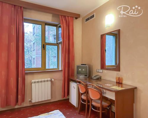 a room with a desk with two chairs and a television at Hotel Rai in Sofia