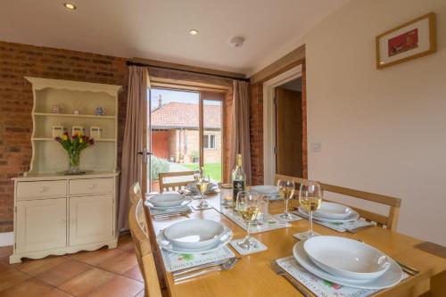 a dining room with a table with plates and wine glasses at The Dairy in Great Massingham