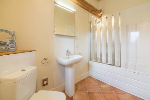 a white bathroom with a toilet and a sink at The Dairy in Great Massingham