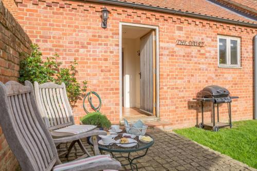 a patio with two chairs and a table and a grill at The Dairy in Great Massingham