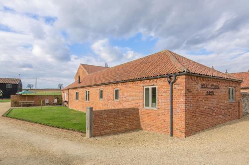 a brick building with a fence in front of it at The Dairy in Great Massingham