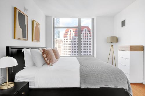 a white bedroom with a large bed with a window at Downtown 1BR w Gym WD nr S Station BOS-619 in Boston