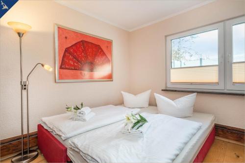 - une chambre avec 2 lits avec des draps blancs et un parasol dans l'établissement Ferienhaus Janina Ferienhaus Janina, à Zinnowitz