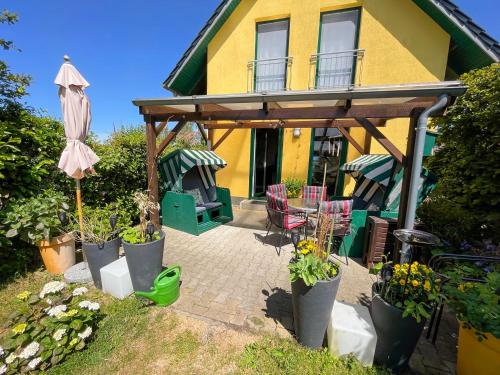 a yellow house with a patio with chairs and an umbrella at Ferienhaus am kleinen Hafen in Neuendorf