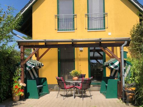 a patio with chairs and a table in front of a yellow building at Ferienhaus am kleinen Hafen in Neuendorf