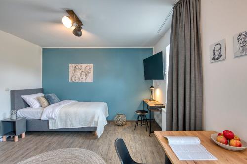BLEIBEREI Apartments في غوتنغن: غرفة نوم بحائط ازرق وسرير بطاولة