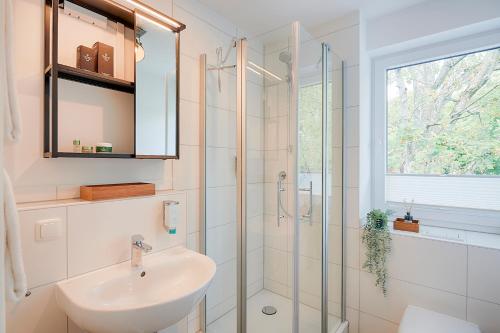 a bathroom with a sink and a glass shower at BLEIBEREI Apartments in Göttingen