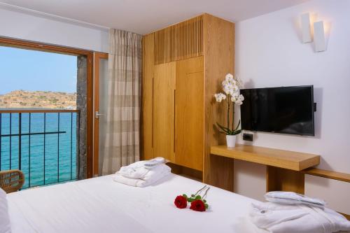 a hotel room with a bed and a large window at Casa di Plaka in Elounda