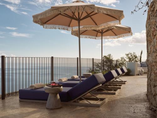 a row of lounge chairs under an umbrella at Verdante Villas in Agios Nikolaos