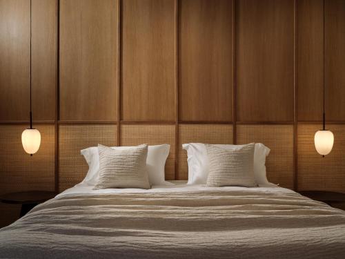 a bed with two pillows and two lights on it at Verdante Villas in Agios Nikolaos
