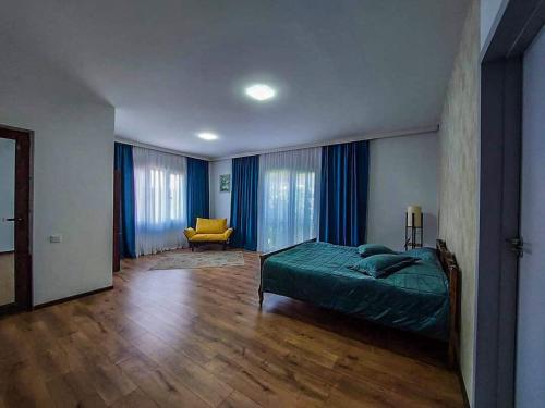 Un dormitorio con una cama verde y una silla amarilla en 4 room house in keda, near Batumi, en K'eda