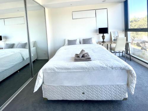 a bedroom with a large white bed and a desk at Brand New Stylish 1BR Apartment, Specious Space, Free Parking, Self Check-in in Canberra