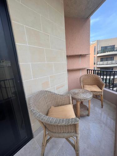 - Balcón con mesa y 2 sillas de mimbre en 2 Bedroom Apartment, en Marsaskala
