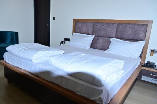 1 cama grande con sábanas y almohadas blancas en HOTEL MAYUR, en Pratāpgarh