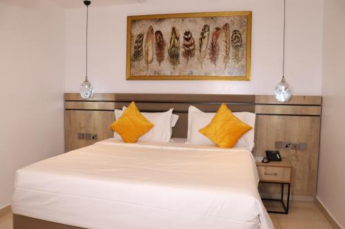 a bedroom with a large white bed with yellow pillows at Top7 Orlando in Abuja