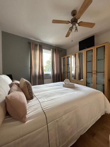 um quarto com uma grande cama branca e uma ventoinha de tecto em no.6 overnight stays em Hindlip