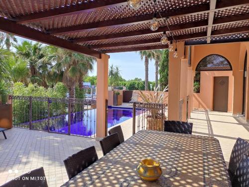 een patio met een tafel en stoelen en een zwembad bij Chambre Emeraude, Riad 9 Couple only au village naturiste in Cap d'Agde