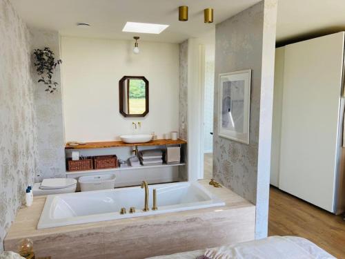 a bathroom with a tub and a toilet and a sink at Sweet Valley View - Architectenwoning in Zutendaal