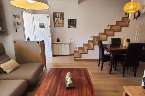 sala de estar con sofá, mesa y escaleras en Preciosa casa adosada, en Castelldefels