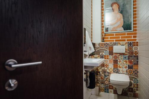uma casa de banho com um lavatório, um WC e uma pintura em Капсульний готель Добрий sleep&eat em Dnipro