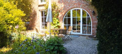 een patio met een tafel en stoelen en een raam bij Upleward Cottage in Krummhörn