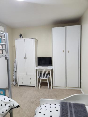 ein Schlafzimmer mit weißen Schränken und einem Schreibtisch in der Unterkunft Room in Crawley/Gatwick/West Sussex in Ifield