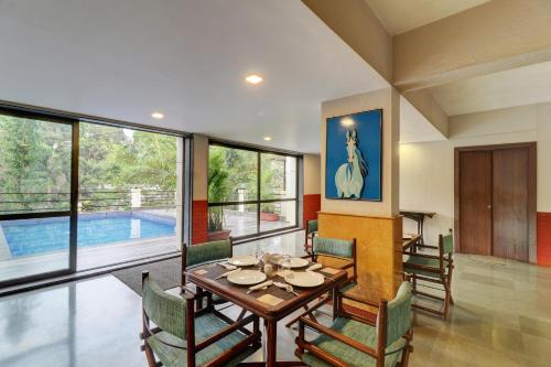 a dining room with a table and chairs and a pool at Amazinn Villa in Lonavala