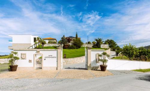 een wit gebouw met een poort voor een huis bij Hotel Cotto do Gatto in Ponte da Barca