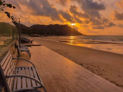 a sunset on the beach with benches on a boardwalk at An Hoa Residence in Long Hai