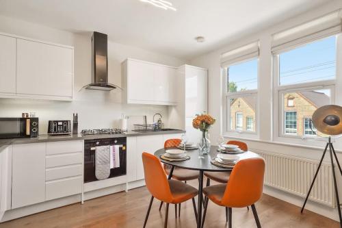 a kitchen with a table and orange chairs in a kitchen at 2 Bed Duplex Apartment in Wimbledon in London