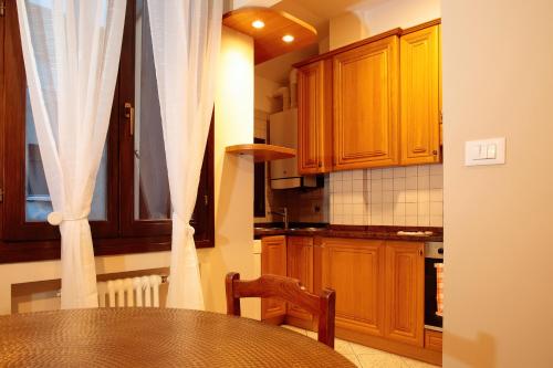 a kitchen with wooden cabinets and a table with a chair at Saint Charles Apartment in Bologna