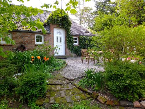 een tuin met een witte deur en een tafel en stoelen bij Upleward Cottage in Krummhörn
