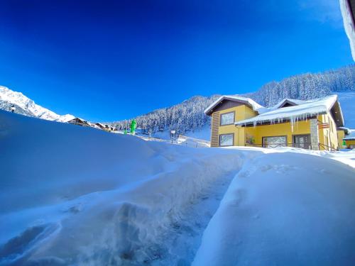 a house in the snow with a snow covered driveway at Arco Hotels & Resorts sonamarg in Sonāmarg
