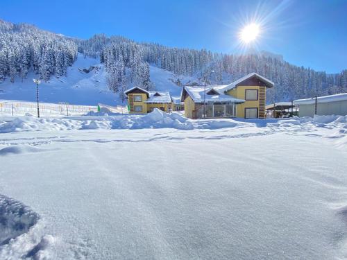 a snow covered road in front of a house at Arco Hotels & Resorts sonamarg in Sonāmarg